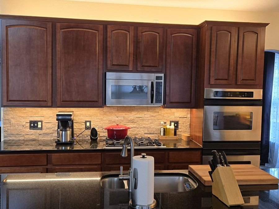 Kitchen with under-cabinet lighting on the backsplash and a warm glow above the upper cabinets