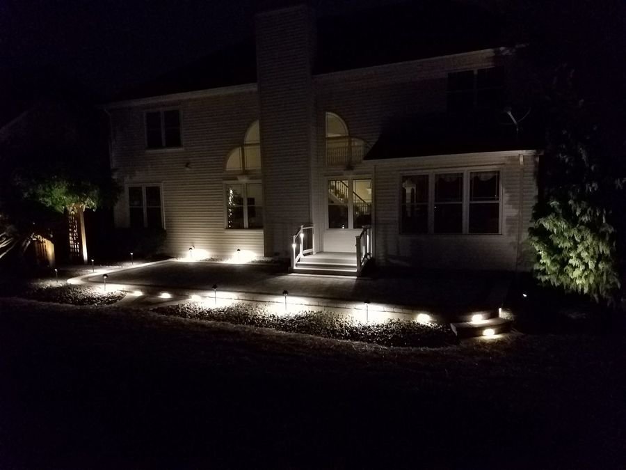 Rear elevation of a home lit with warm path and bed lighting